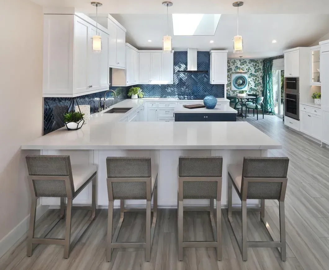 Modern kitchen with white cabinets, blue backsplash, and island with bar stools.