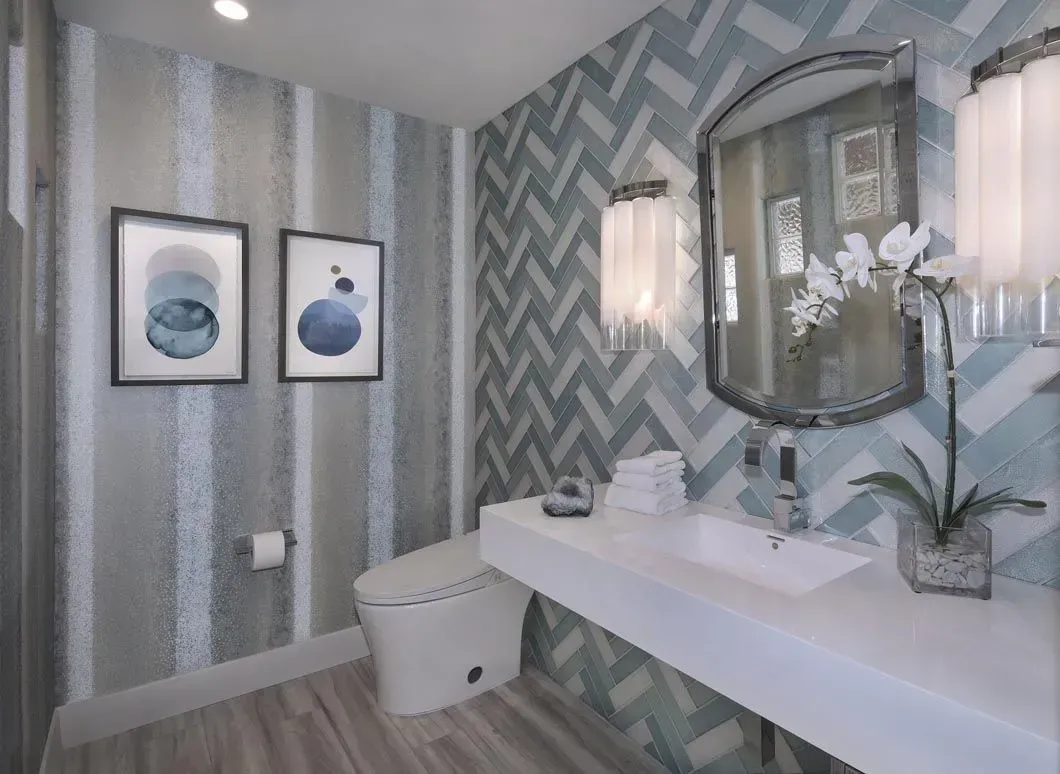 Bathroom with blue and white patterned walls, white sink, and silver-framed mirror.