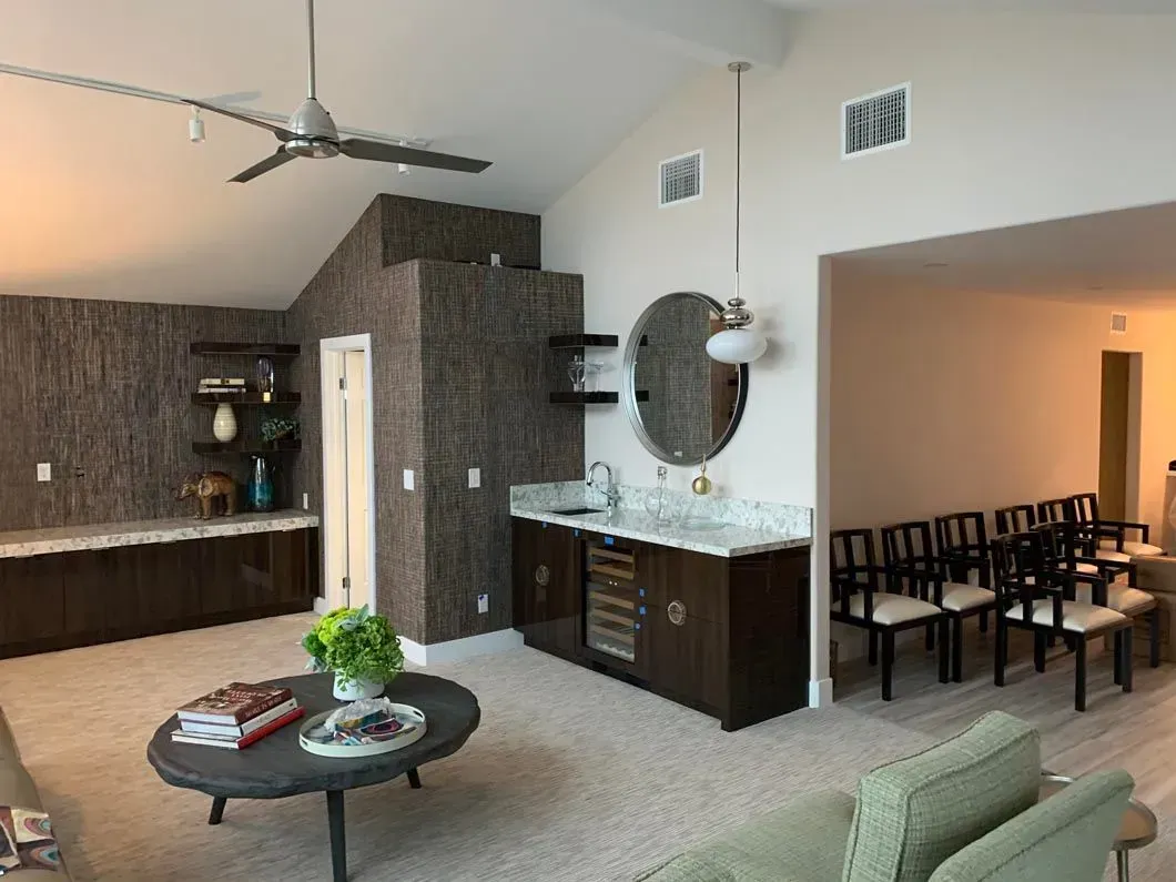 Bar area with built-in cabinetry, stone accent wall, and a round coffee table in a room with light flooring.