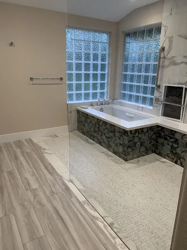 Bathroom with a bathtub, frosted glass windows, and light-colored tile floors and walls.