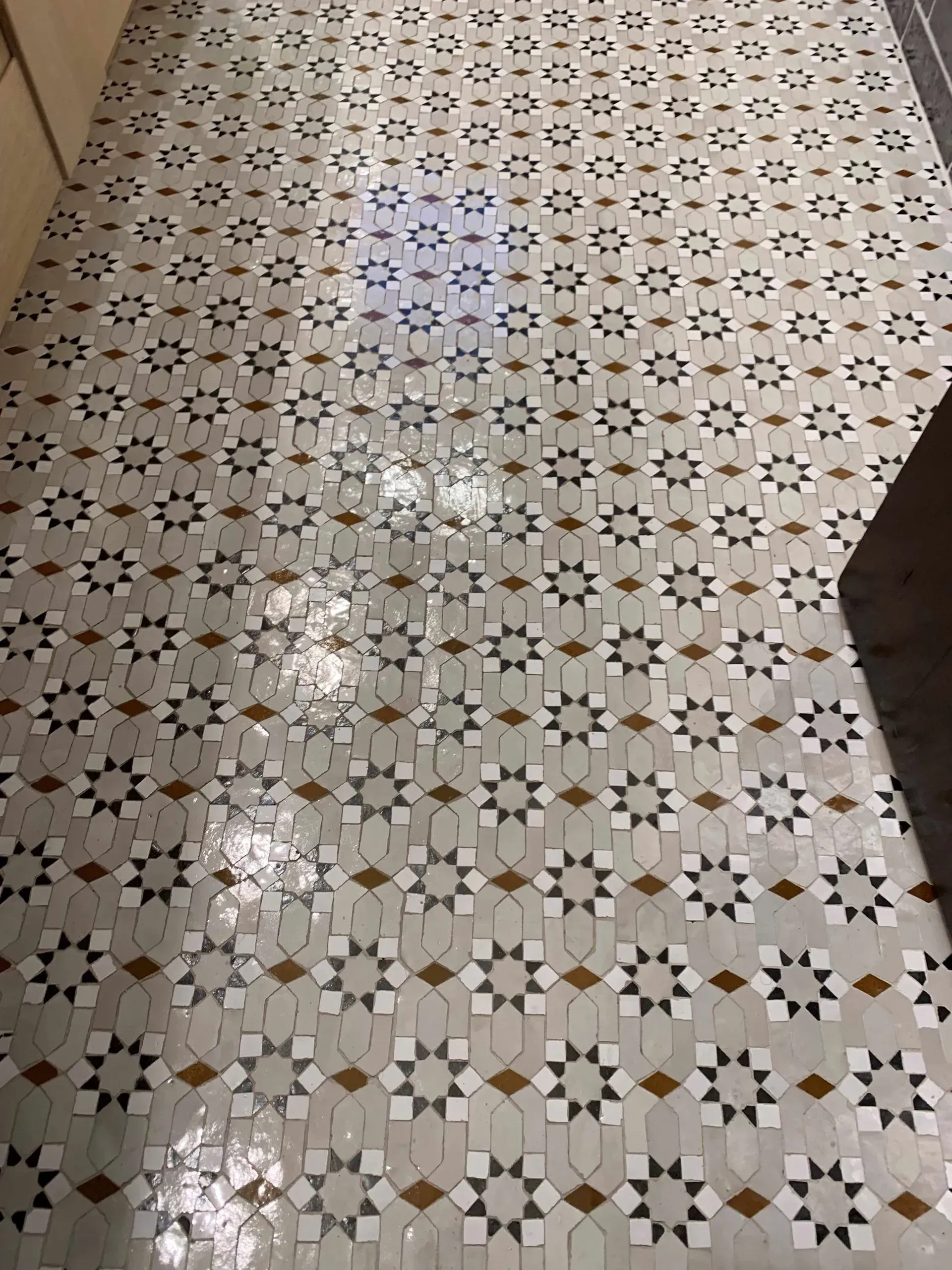 Geometric tile floor with a floral pattern in gray, white, brown, and black.