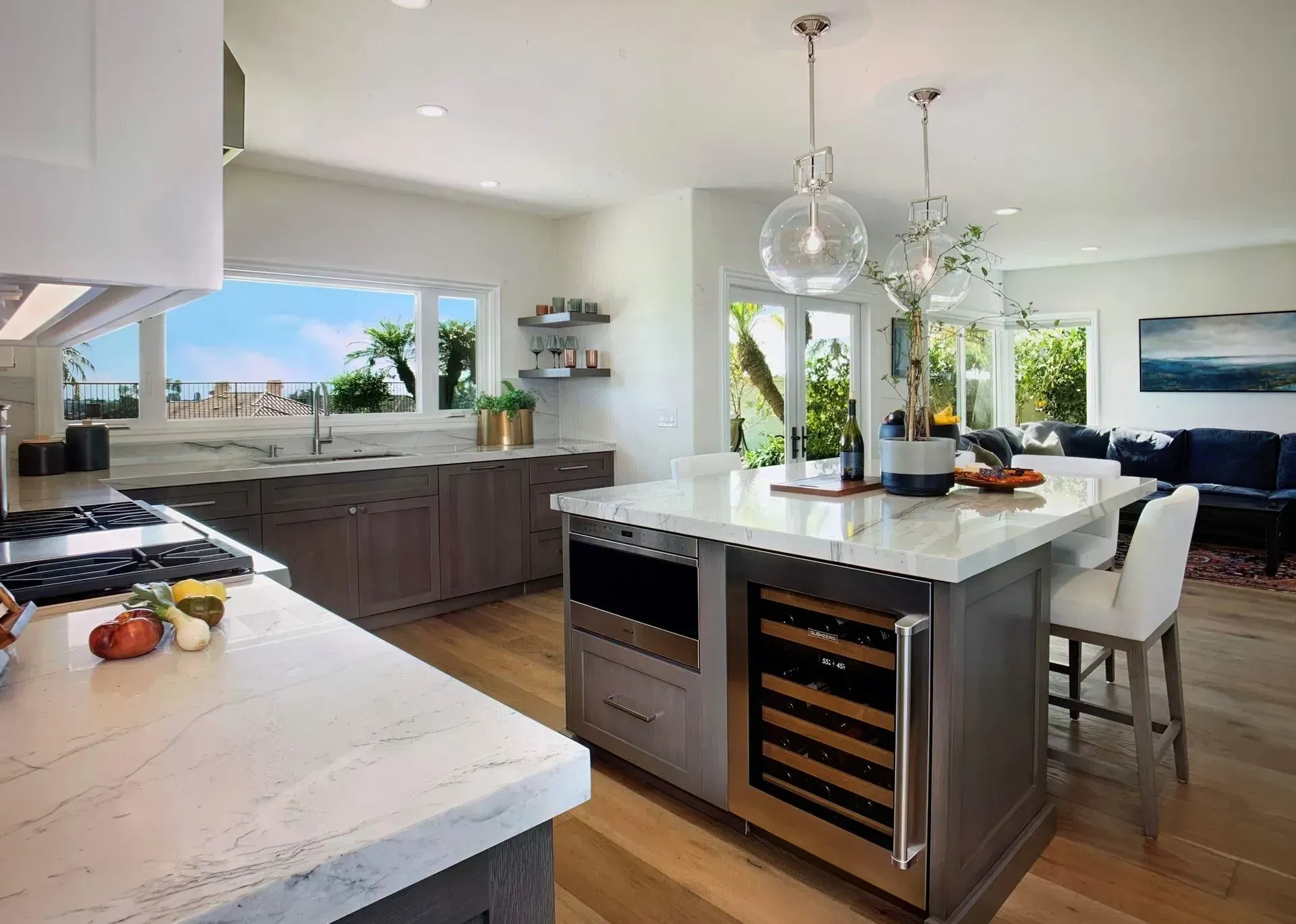 Modern kitchen with island, marble countertops, stainless steel appliances, and wood flooring.