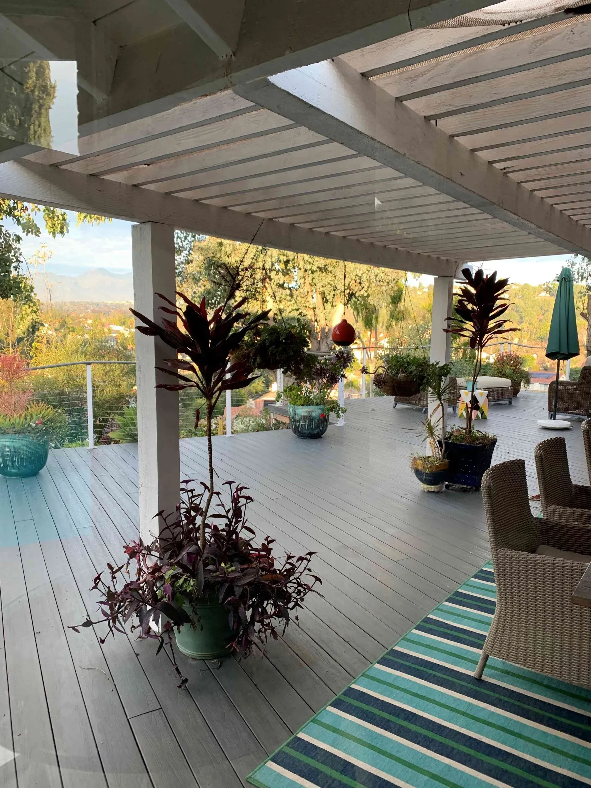 Covered deck with potted plants and a view of trees and mountains.