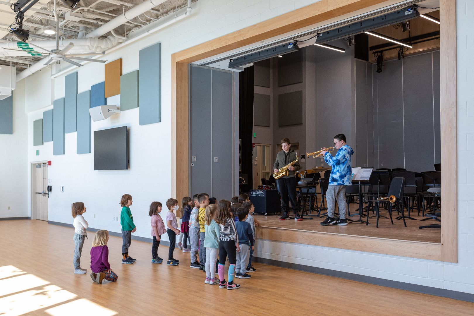 A group of children standing in front of a stage watching a band perform