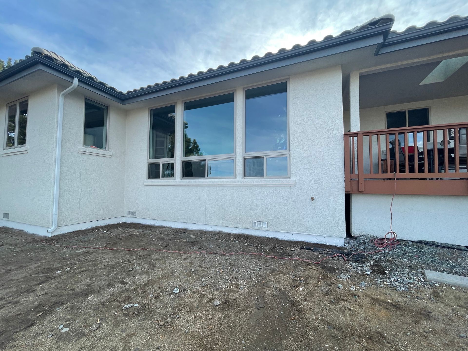 A white house with a porch and a lot of windows that has recently had new stucco installed in Reno, Nevada