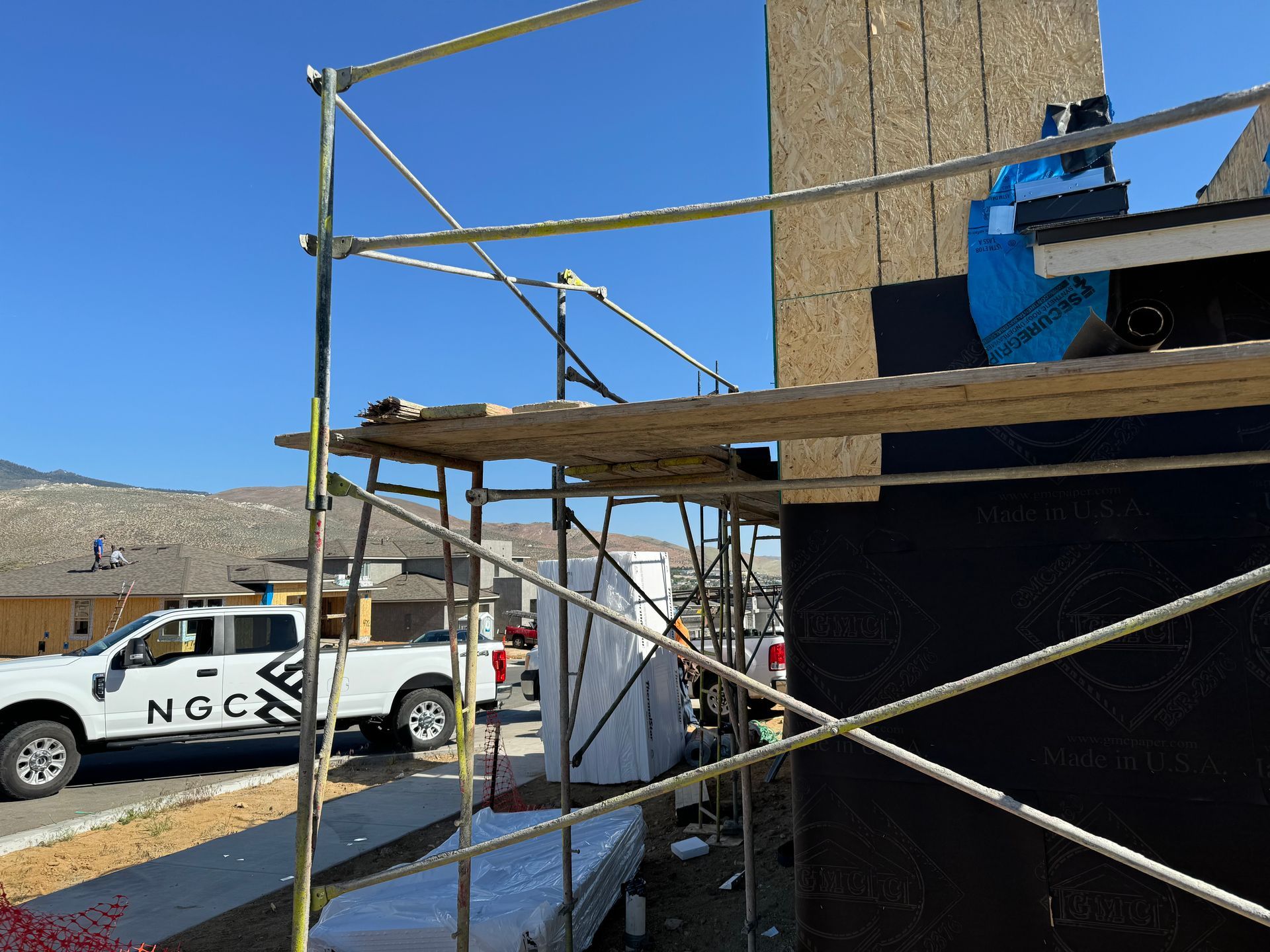 New Generation Construction truck parked in front of a new home that is getting the exterior siding prepped for stucco.
