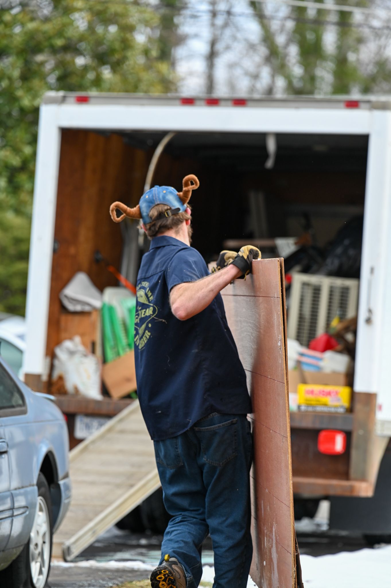 A man wearing a viking hat is loading a truck with a piece of wood.