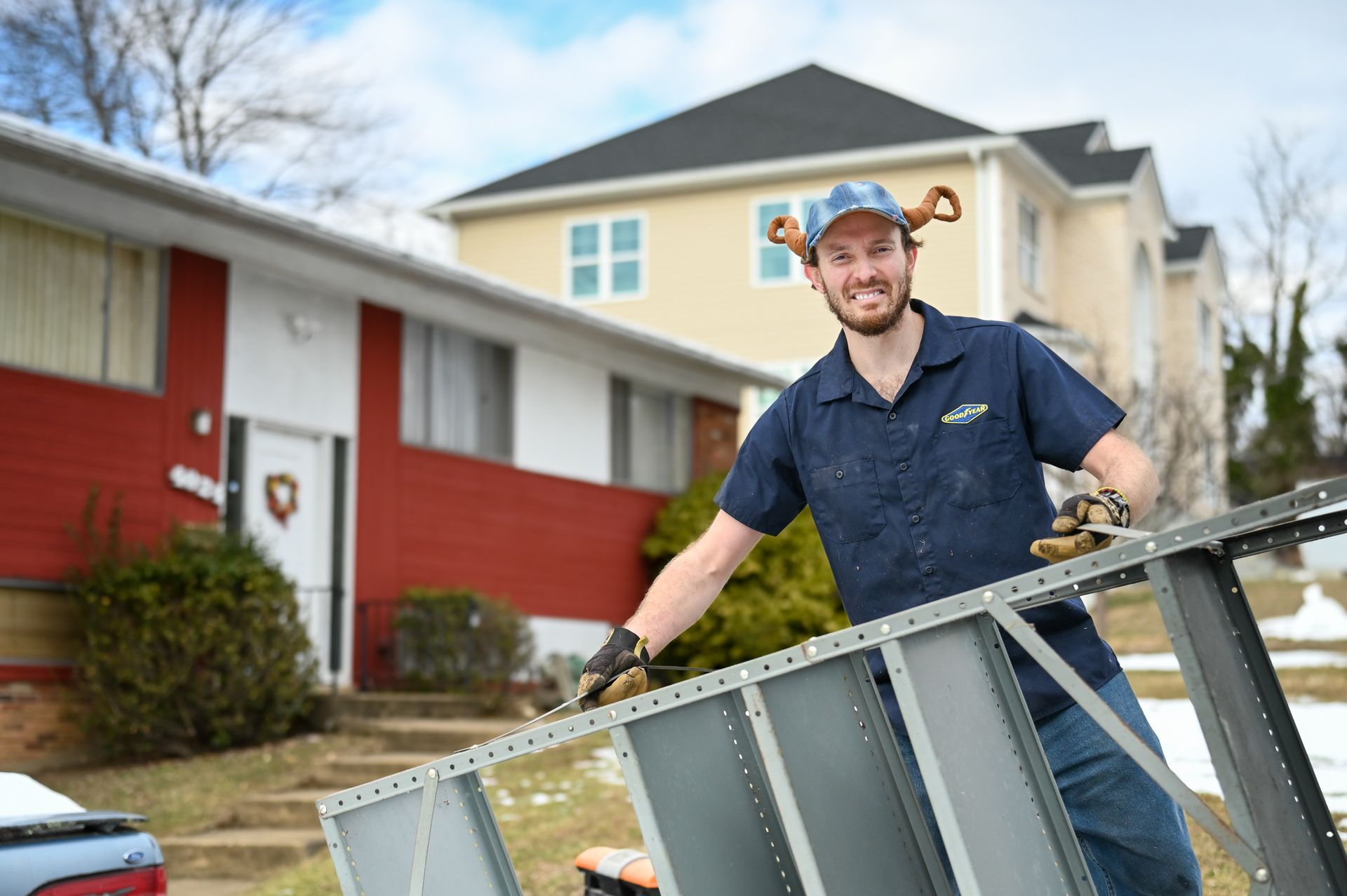 A man is holding a piece of metal in front of a house.