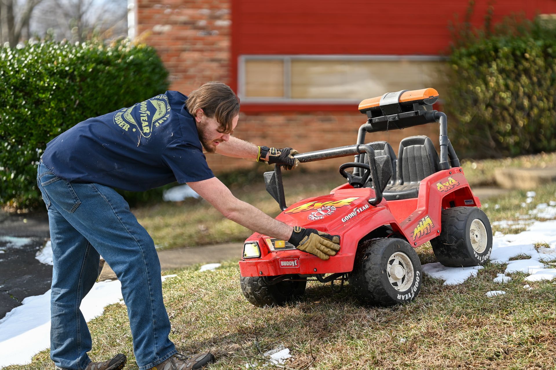 A man is fixing a toy car in the grass.