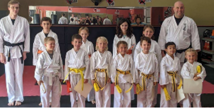 A group of kids in karate uniforms are posing for a picture