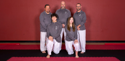A group of people are posing for a picture in front of a red wall.