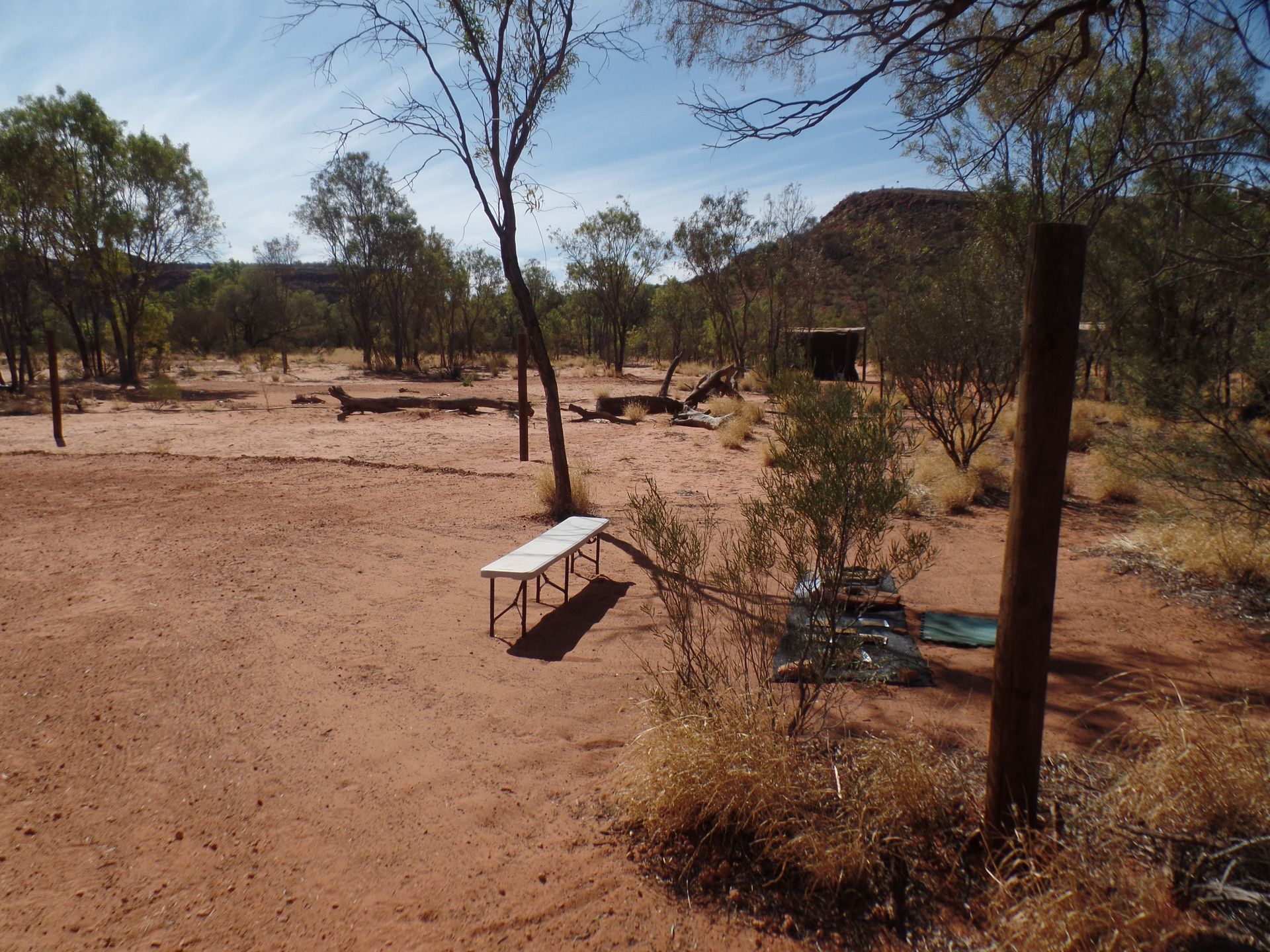 A white bench sits in the middle of a dirt field