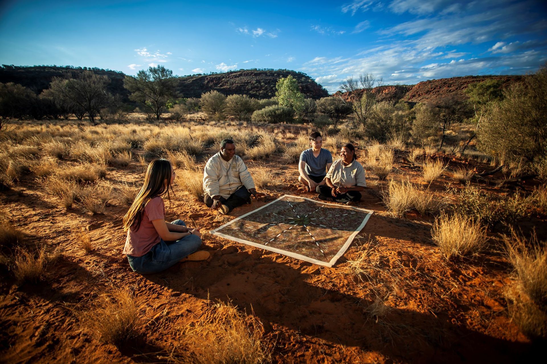 A group of people are sitting on the ground in the desert.