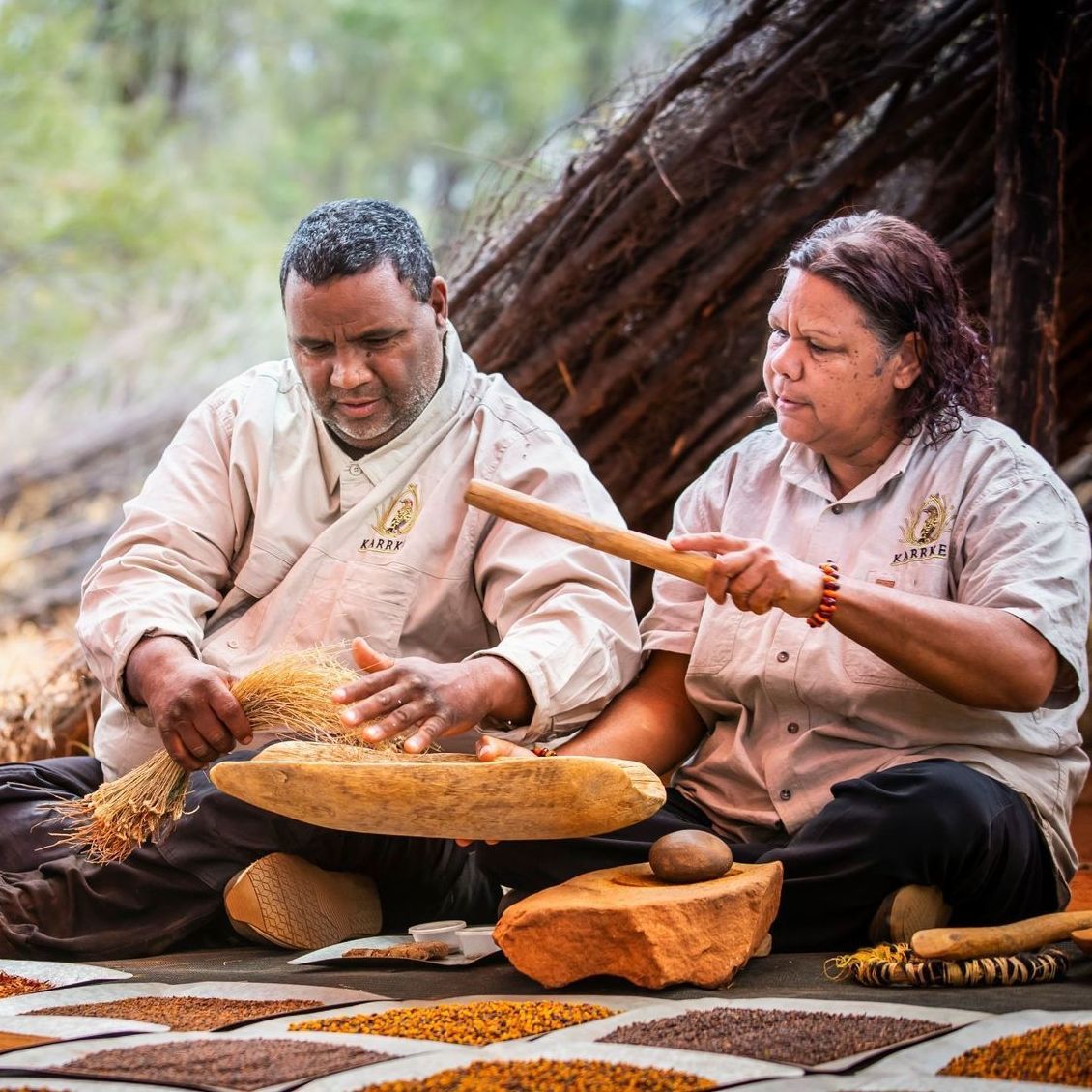 A man and a woman are sitting on the ground making food.