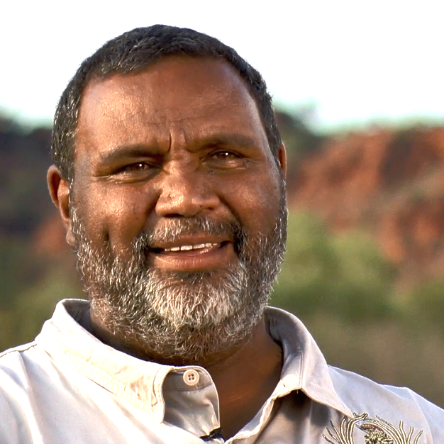 A man with a beard is smiling and wearing a white shirt