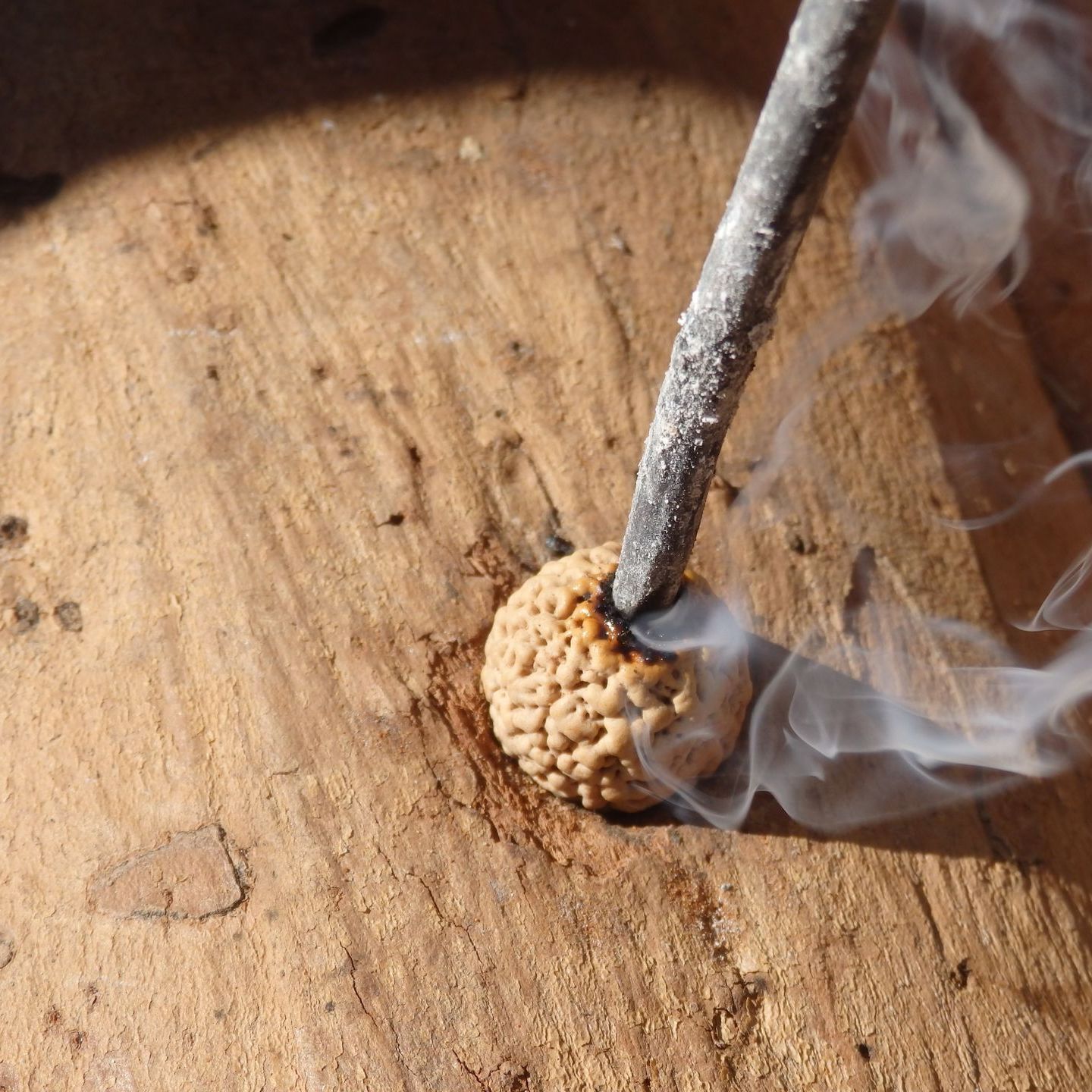 A stick is sticking out of a hole in a piece of wood