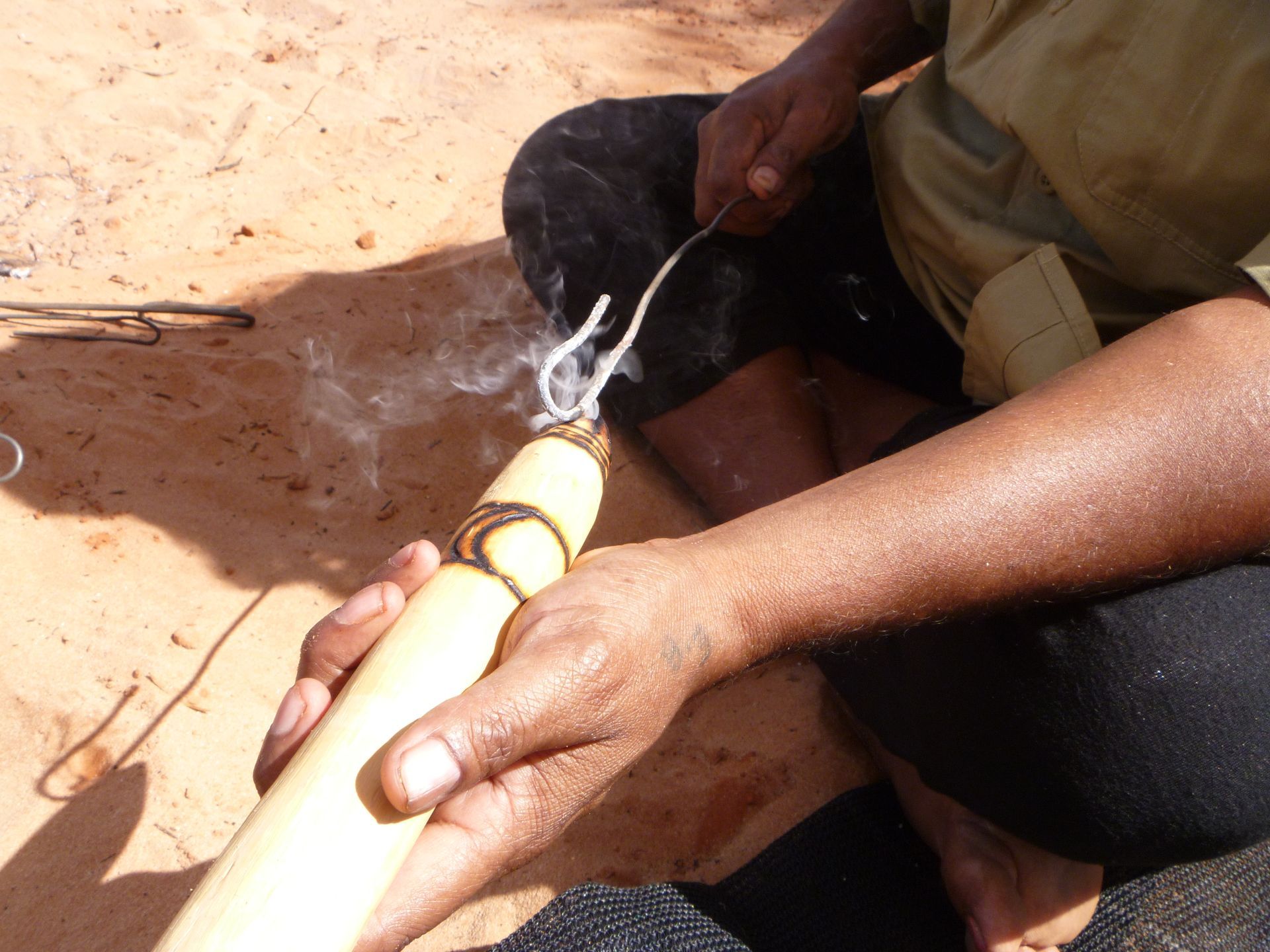 A person is holding a piece of wood with smoke coming out of it