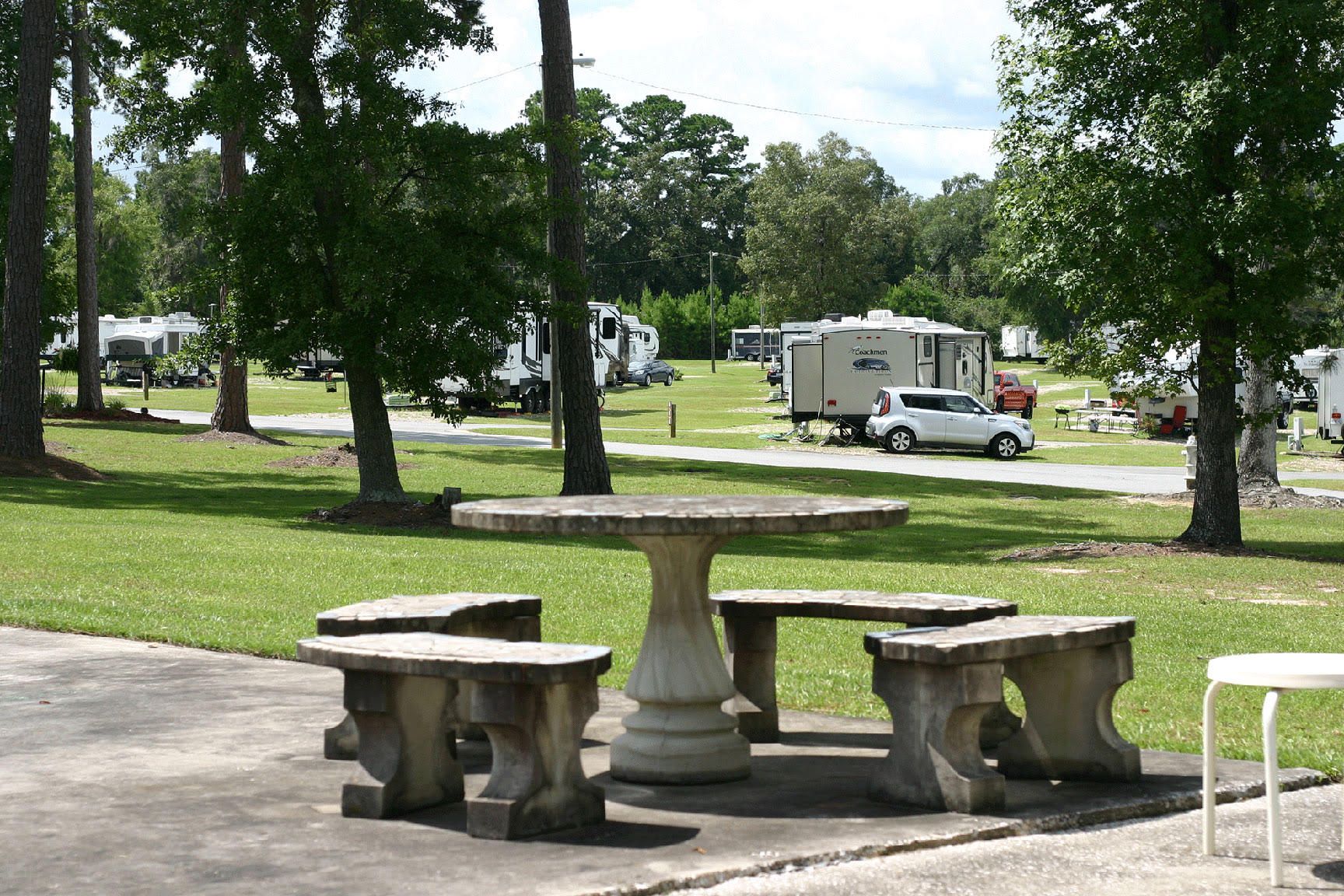 A picnic table and benches in a park with rvs in the background