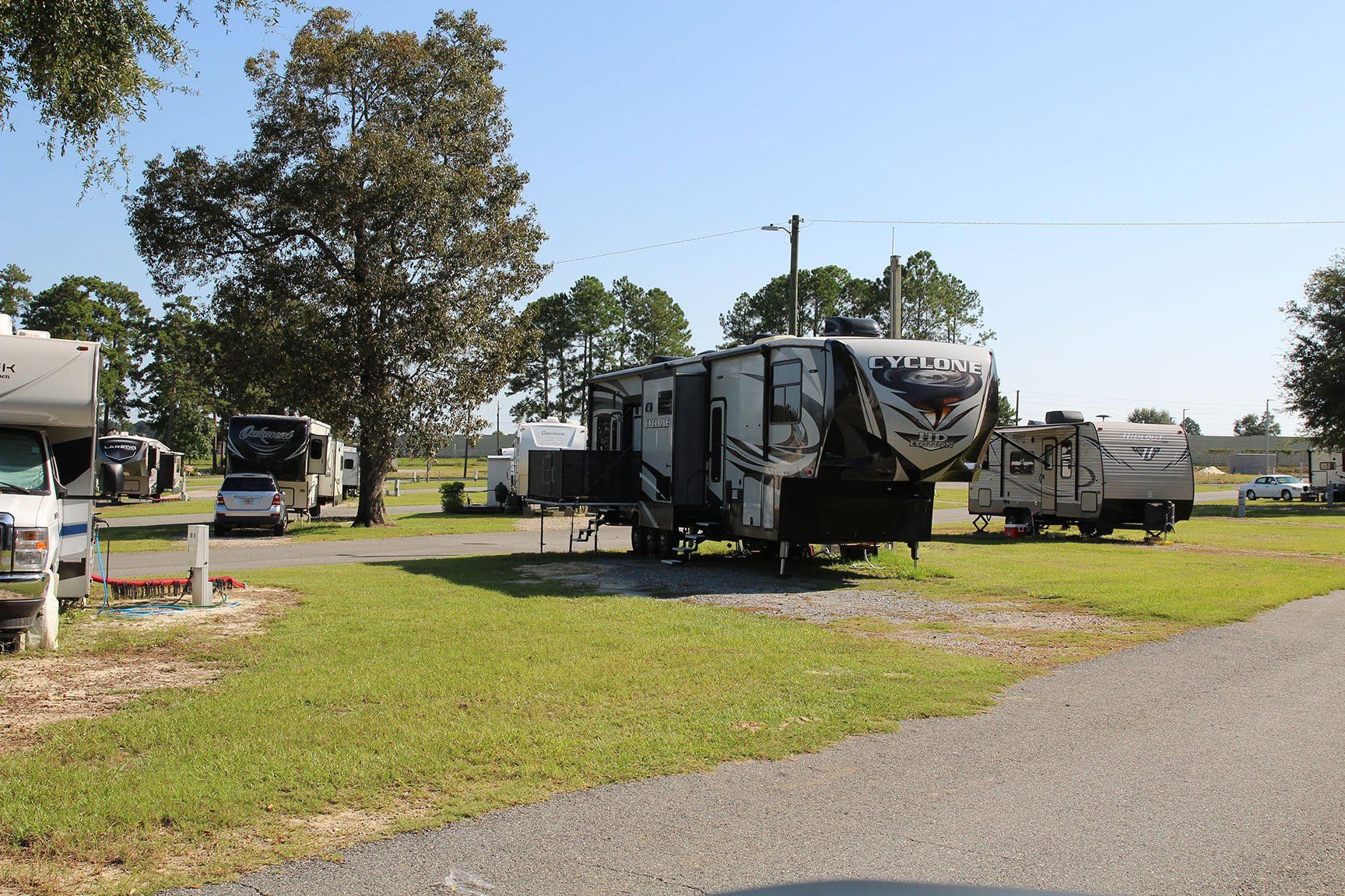 A row of rvs are parked in a grassy field.