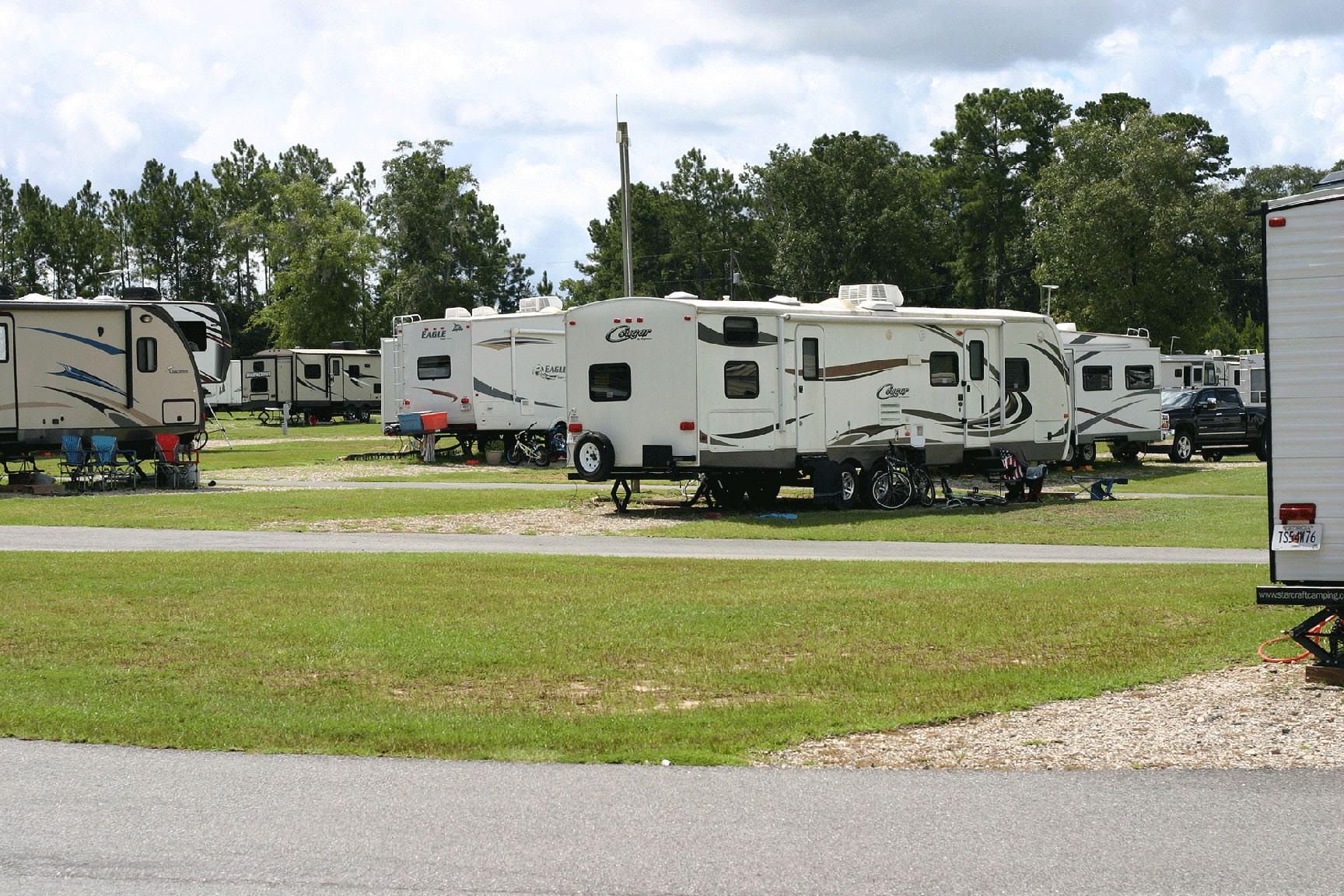 A row of rvs are parked in a grassy field