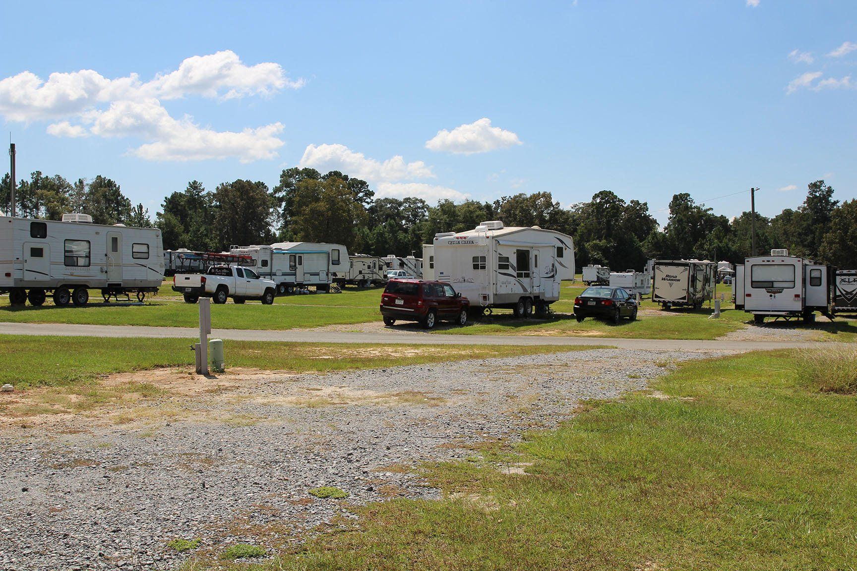 A row of rvs are parked in a grassy field