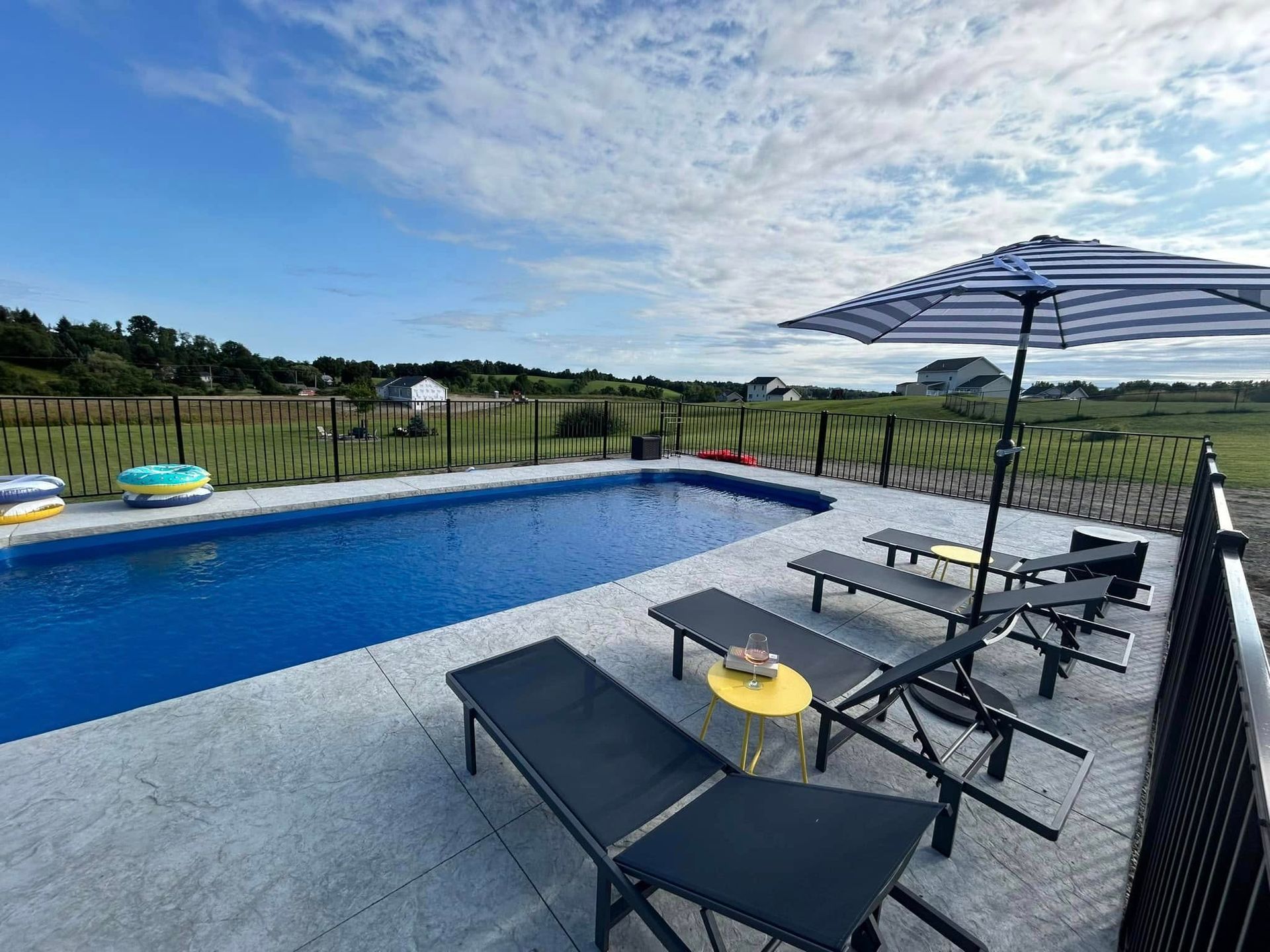 Pool with lounge chairs and umbrella on a sunny day.
