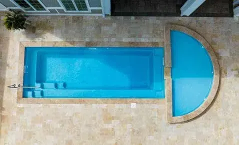 Overhead view of a rectangular pool with steps and a half-circle pool, surrounded by tan stone.