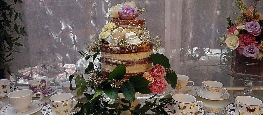 Half-naked baby shower cake with fondant baby shoes and fresh flowers. created by bexx in bexx secret garden