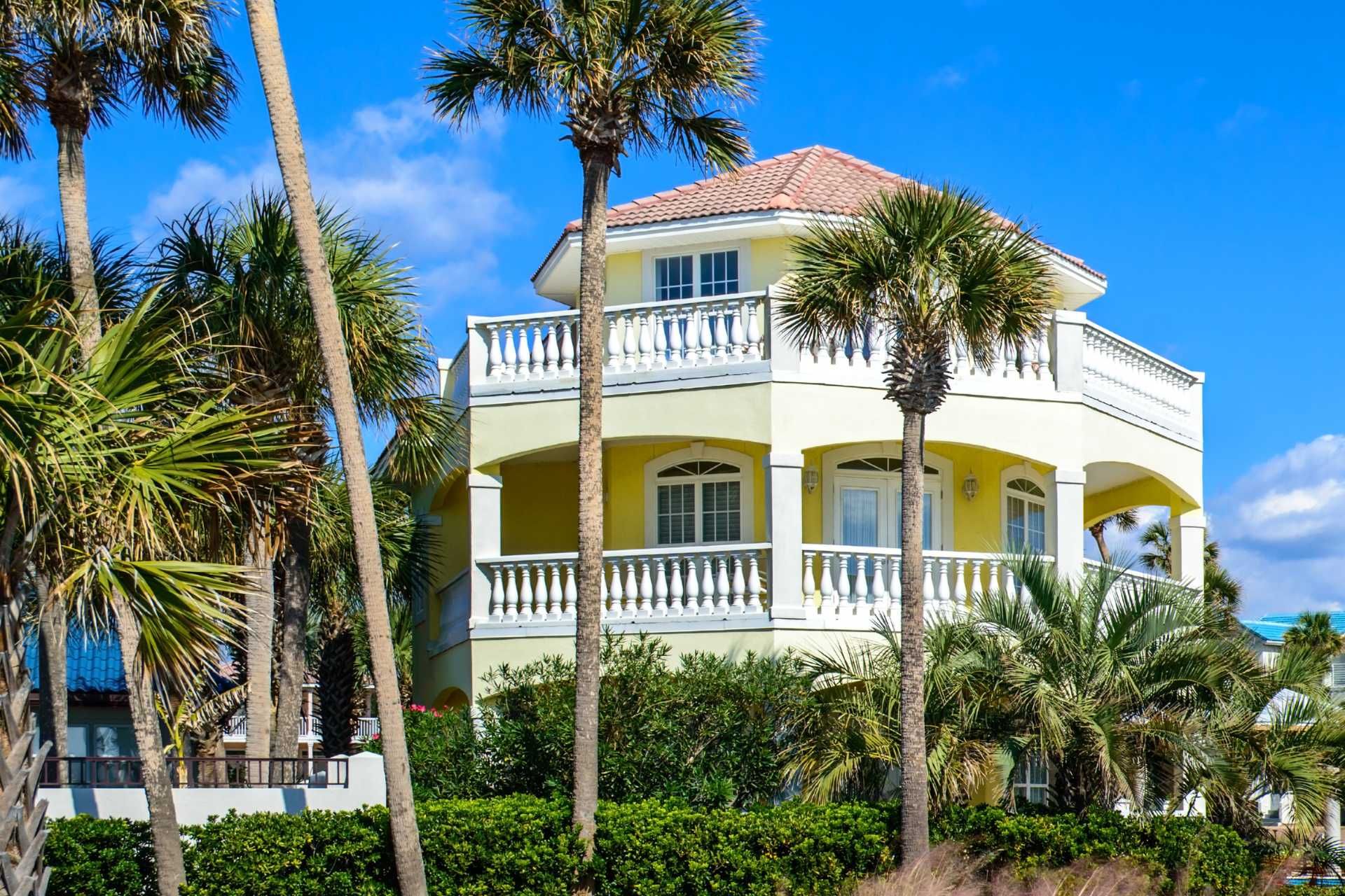 a yellow house with palm trees in front of it