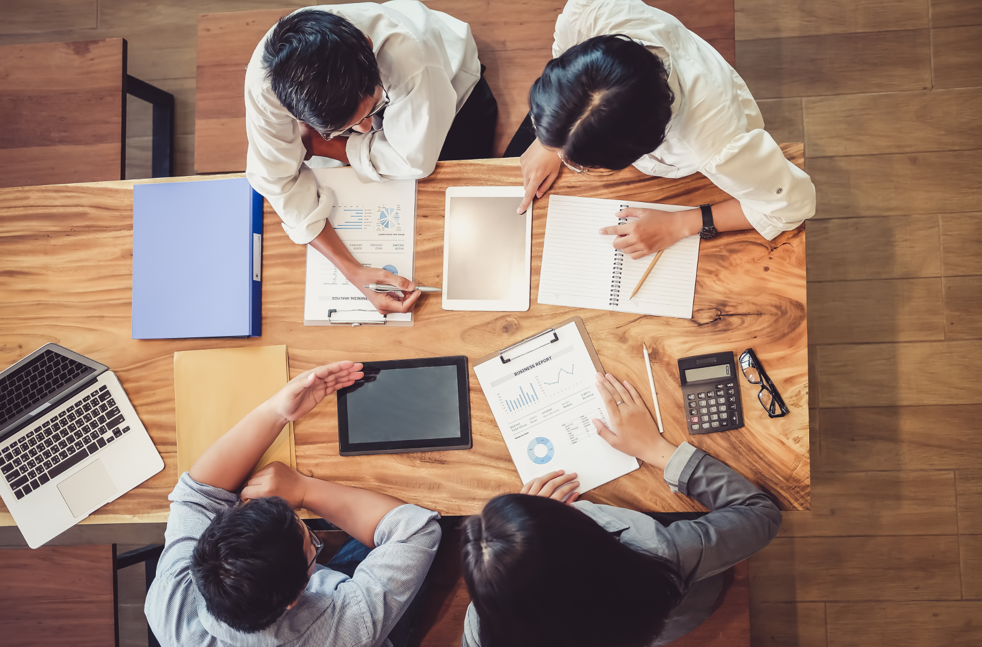 A group of people are sitting around a wooden table.