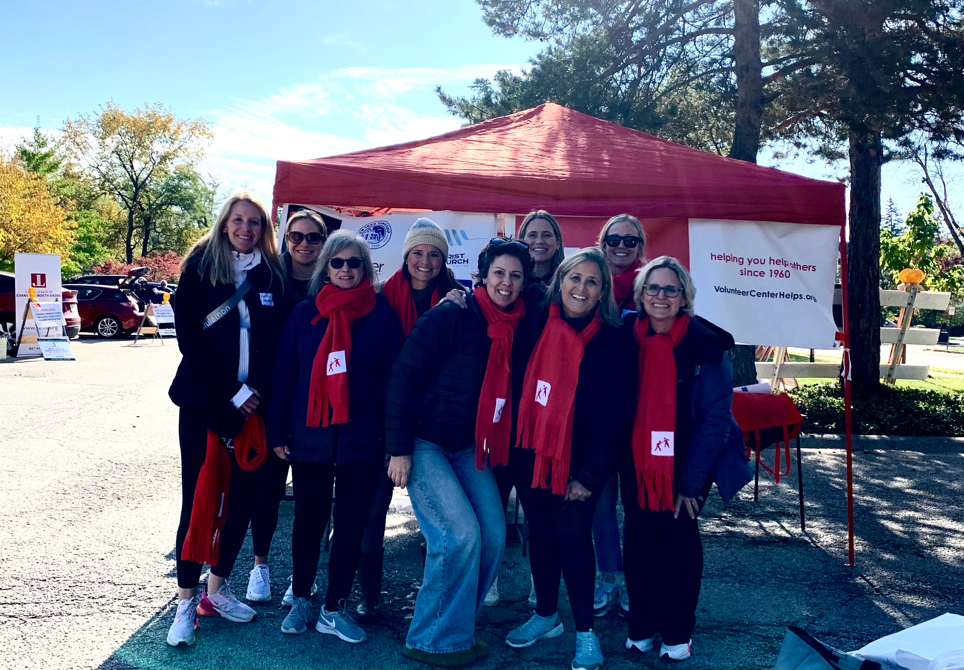 A group of women are posing for a picture in front of a red tent.