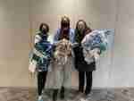 A group of women are posing for a picture in front of a painting.