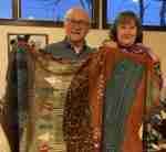 A man and a woman are standing next to each other holding blankets.