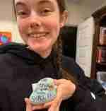 A young girl is holding a cookie in her hands and smiling.