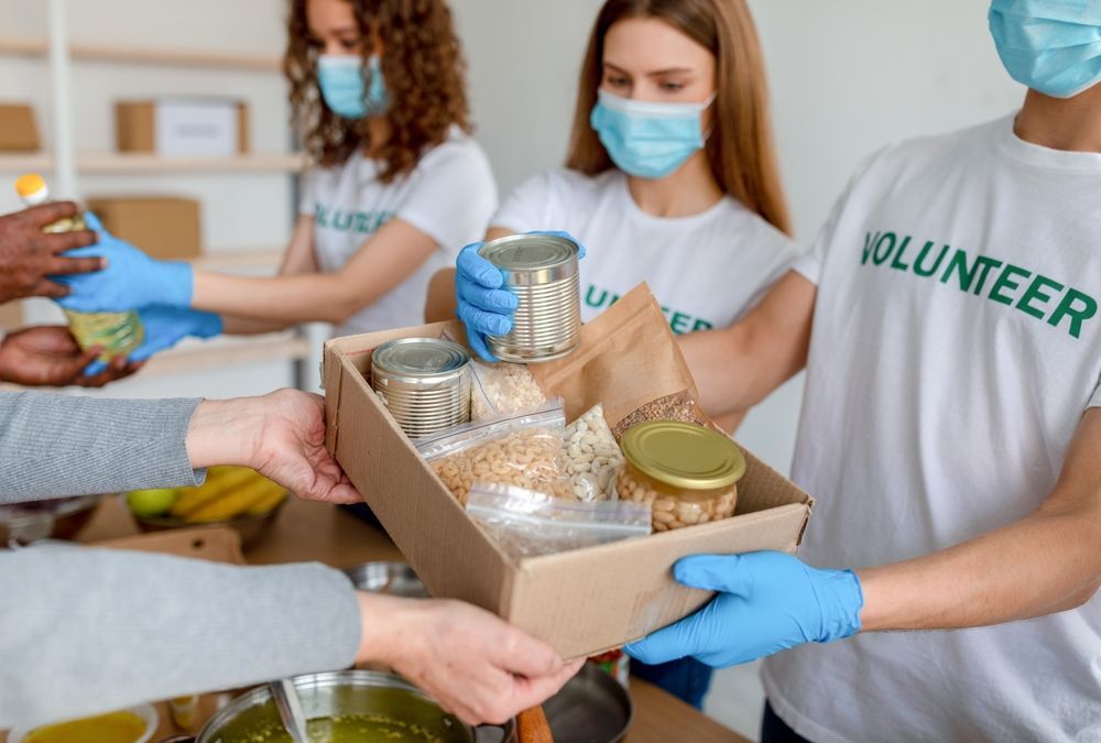 A group of volunteers are holding a box of food.