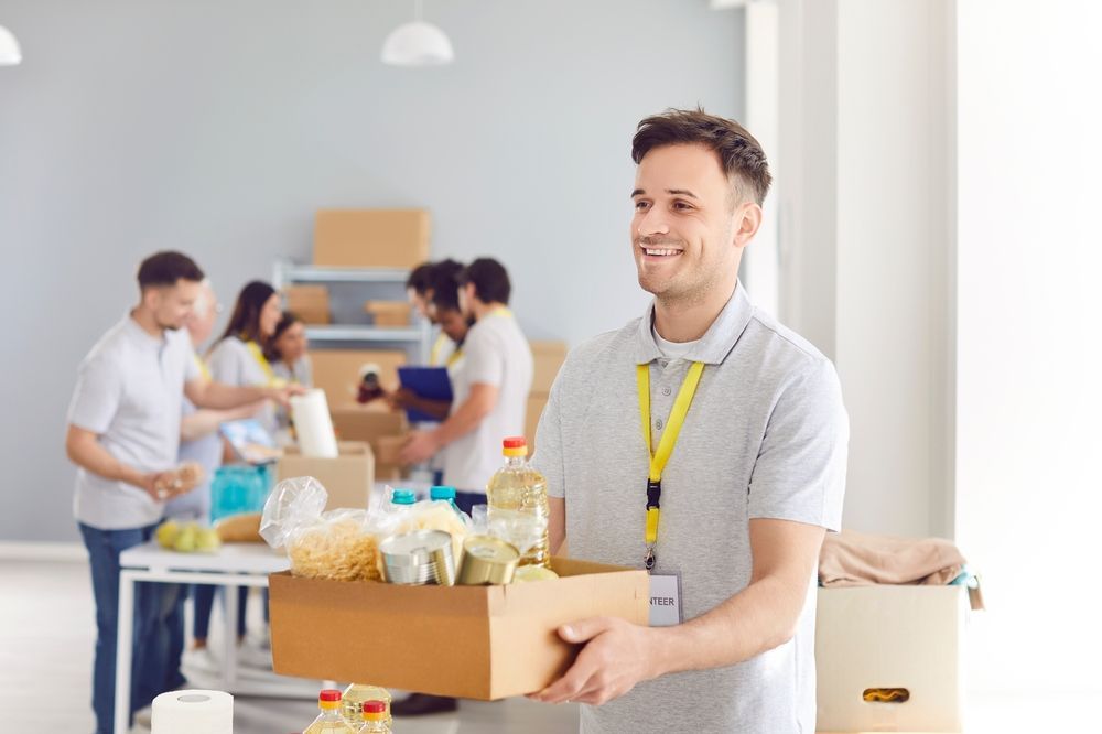 A man is holding a box of food in front of a group of people.