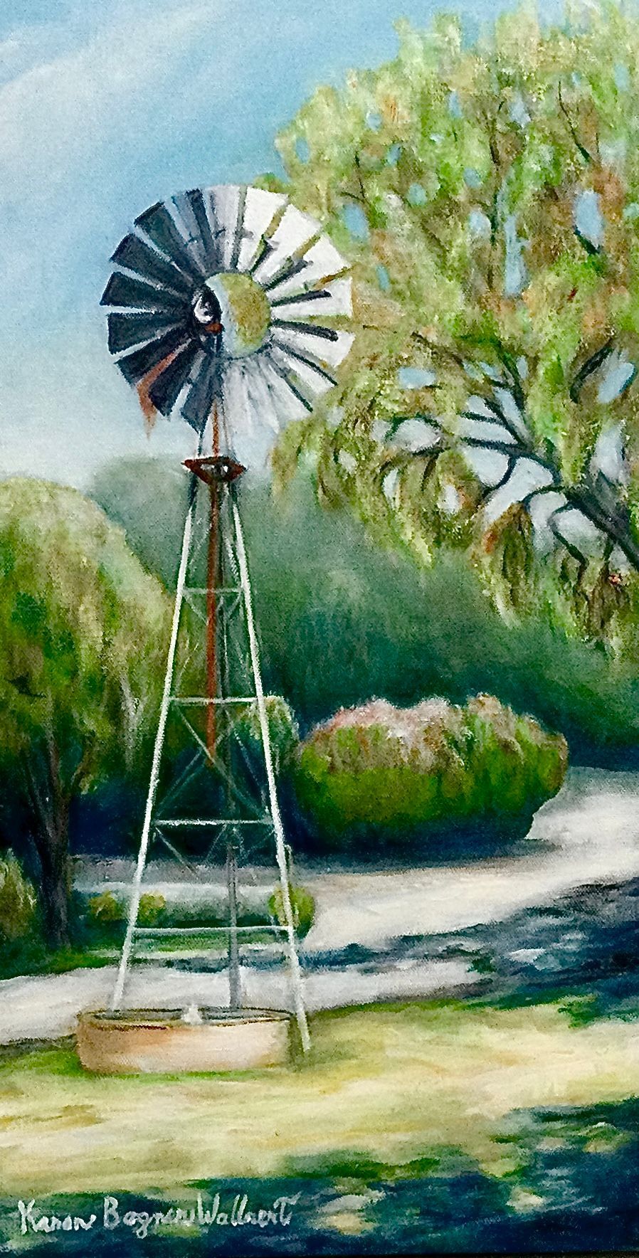 Windmill stands in field with trees and shrubs.