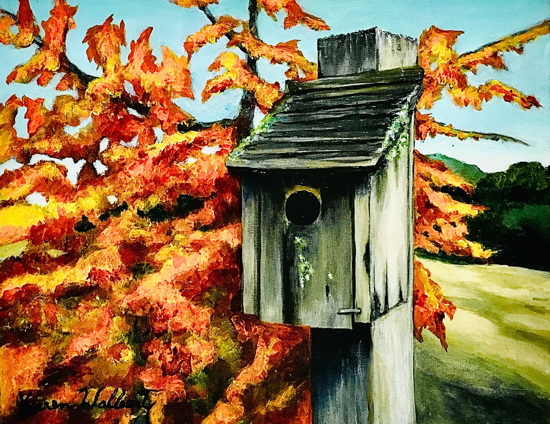 Birdhouse on a weathered post with colorful fall foliage in the background.