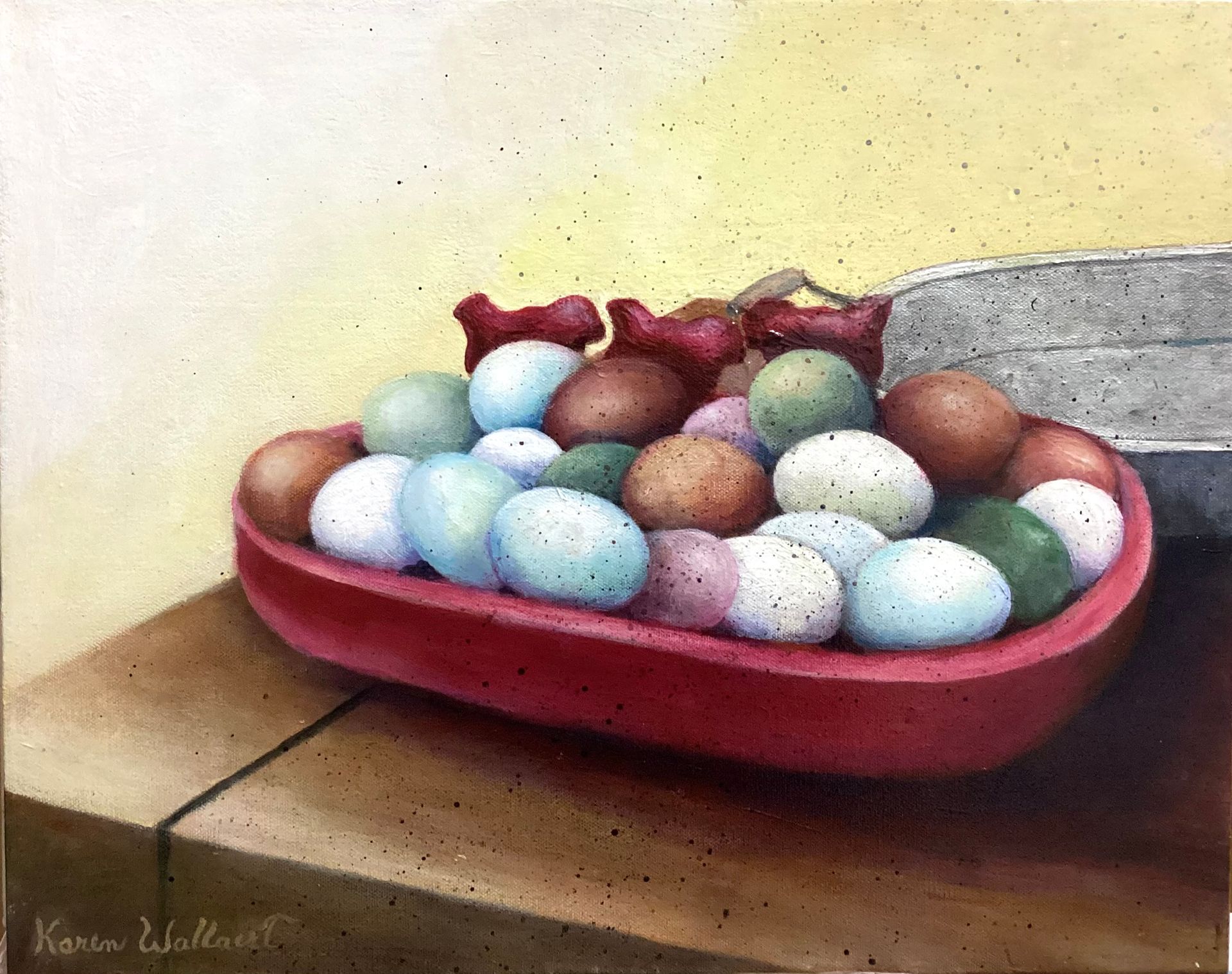 Colorful eggs in a red bowl on a wooden table. Two small red bows on top of the bowl.