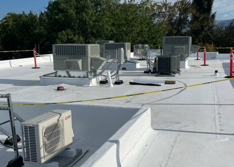 A white roof with a lot of air conditioners on it