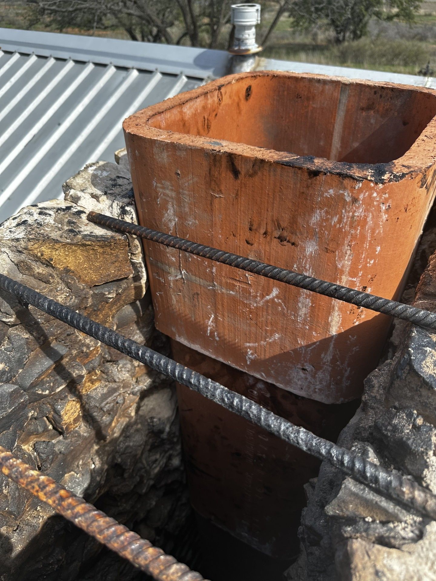 A brick chimney is being built on top of a roof.