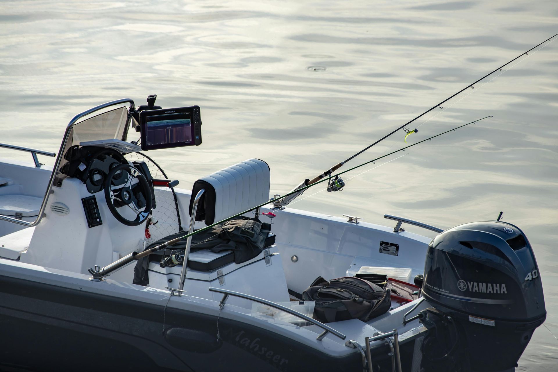 Fishing boat on calm water with a mounted rod, sonar display, and outboard motor