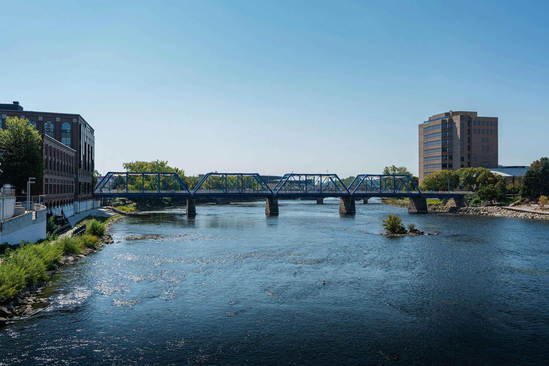 Bridge over a wide river between city buildings on a clear day