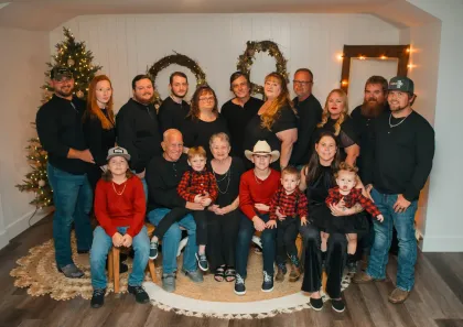 Family portrait with adults and children posing in front of Christmas decorations.