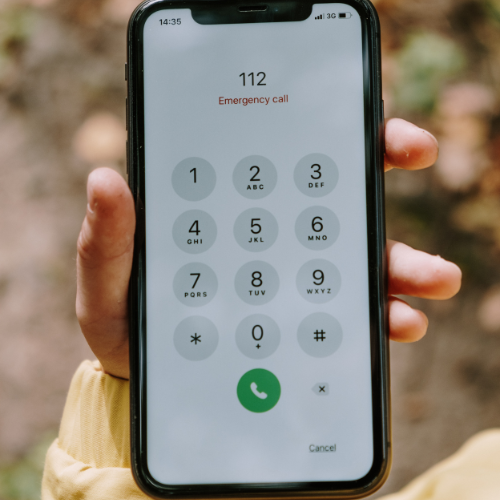 Person dialing 112 on a smartphone for an emergency call.
