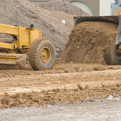 Man in white hard hat and blue shirt with arms crossed, smiling.