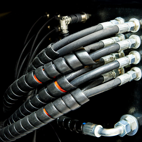 Black hydraulic hoses wrapped in spiral protection, with silver fittings.