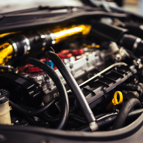 Close-up of a car engine with black and yellow components, including hoses and a dipstick.