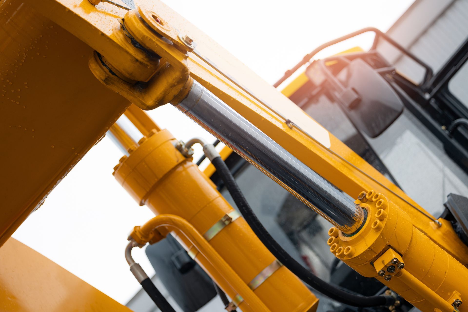 Man works on machinery in a shop; a large cylinder is suspended by chains.
