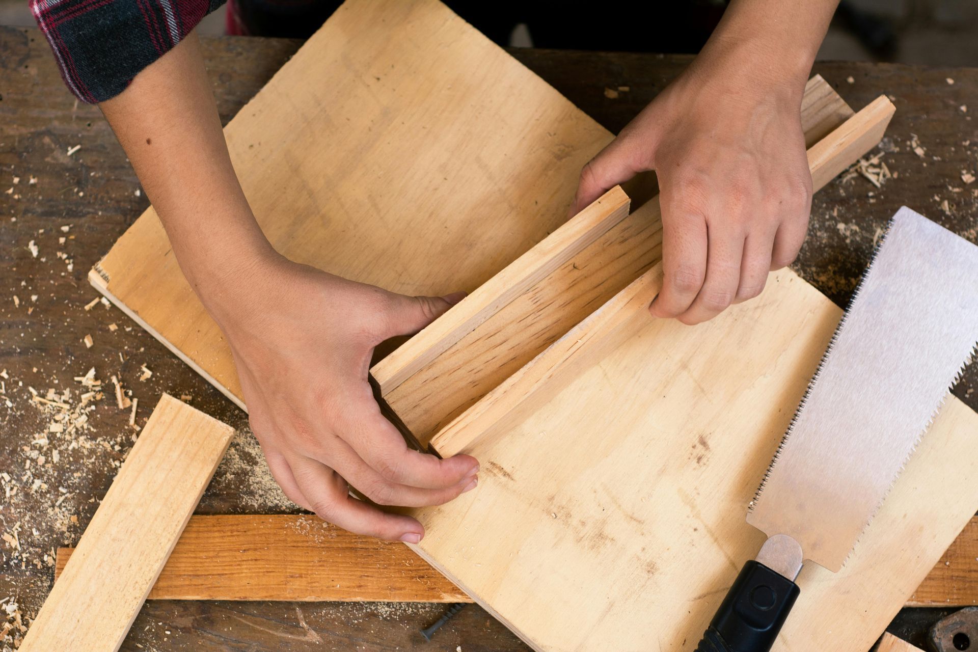 A person is cutting a piece of wood with a saw.